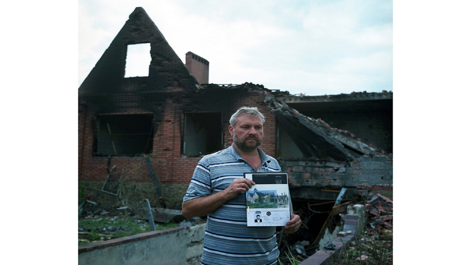 مواطن من مدينة سلوفيانسك يحمل صورة منزله الذي خرب.
