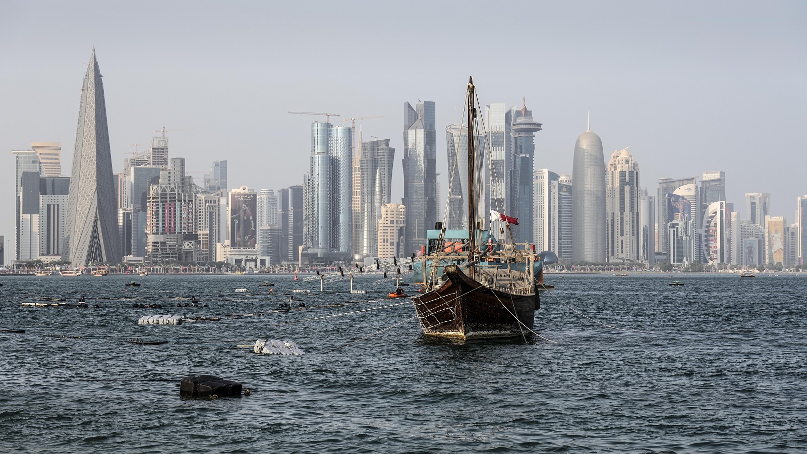 ناطحات السحاب خلف قارب تقليدي في الدوحة (AP)